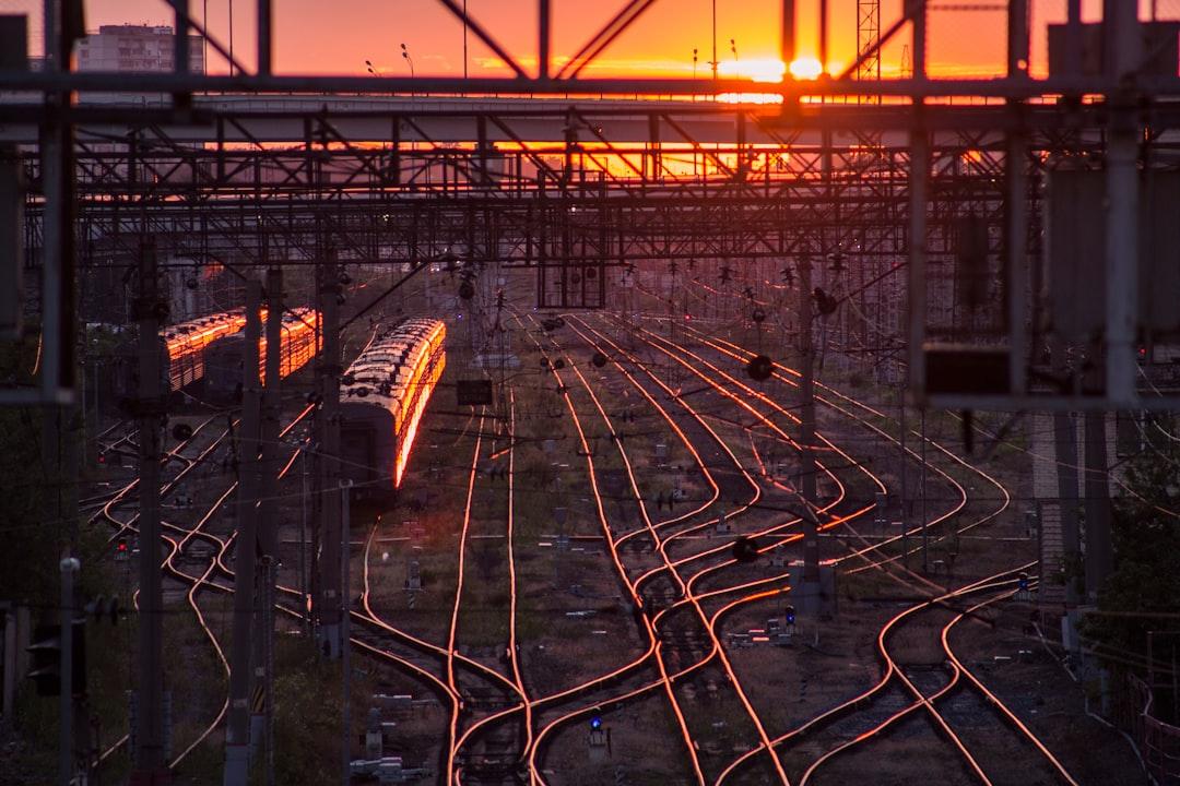 black train on railway during golden hour by Aleksandr Popov